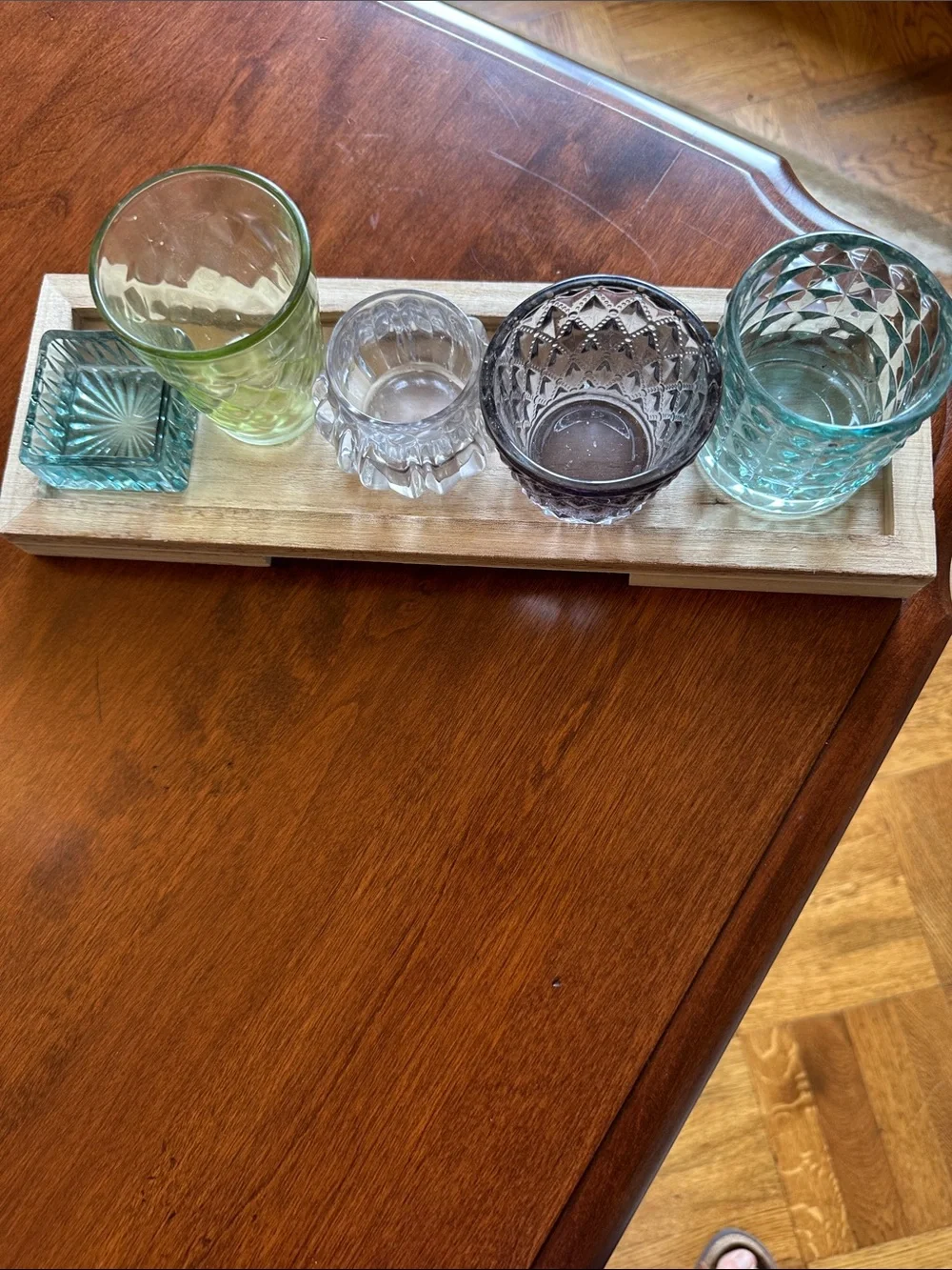 Colorful Glass Votive Set - Blue, Green, Smoke, Clear on a wooden tray.